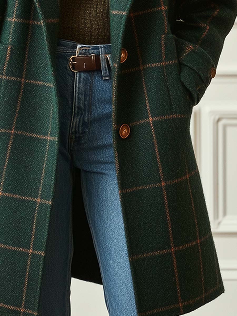 A woman wearing a classic checked belted coat in dark green with a defined waist.