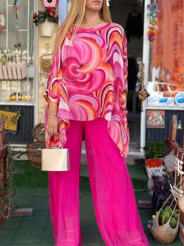A woman wearing a swirl-print top with flowing wide-leg trousers