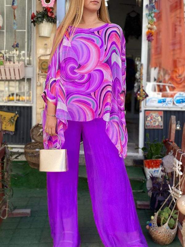 A woman wearing a swirl-print top with flowing wide-leg trousers