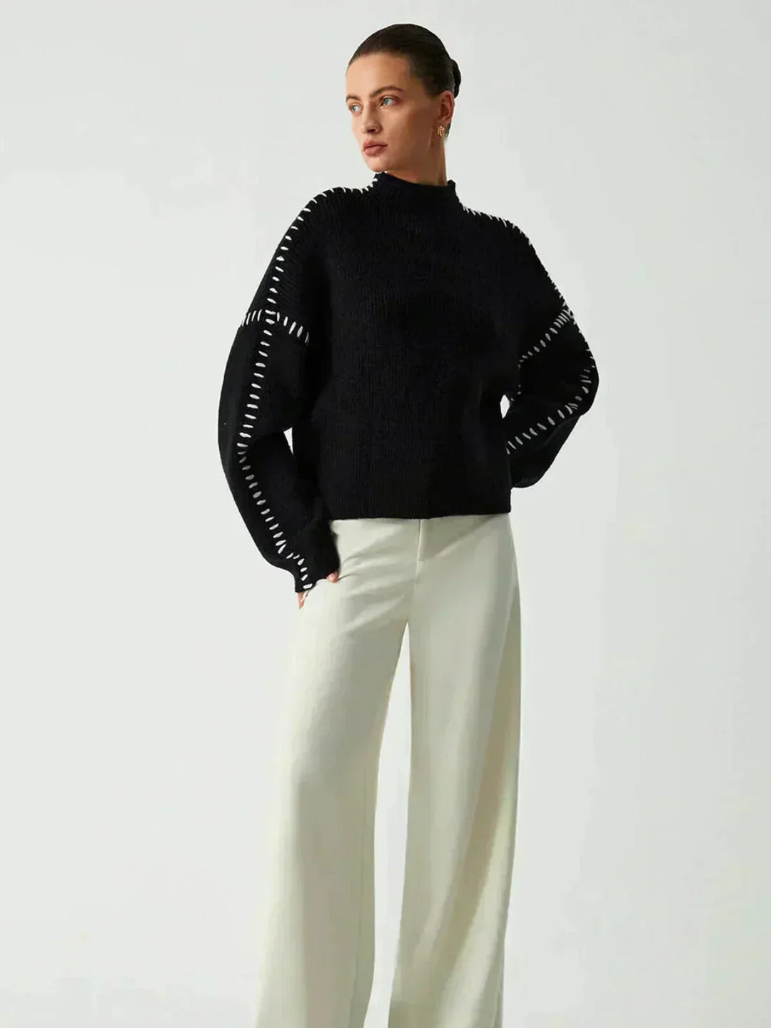 A woman wearing an oversized mock-neck jumper with whipstitch detailing, cosy and stylish.