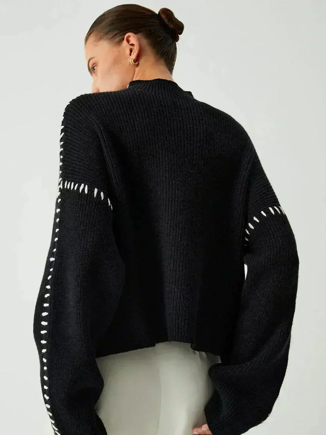 A woman wearing an oversized mock-neck jumper with whipstitch detailing, cosy and stylish.