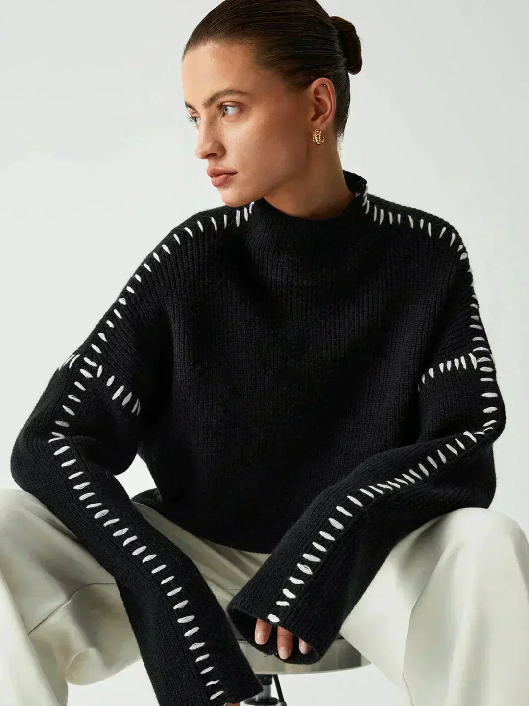 A woman wearing an oversized mock-neck jumper with whipstitch detailing, cosy and stylish.