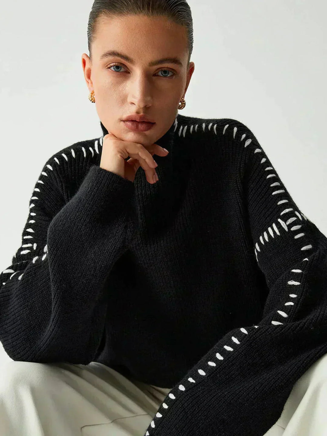 A woman wearing an oversized mock-neck jumper with whipstitch detailing, cosy and stylish.