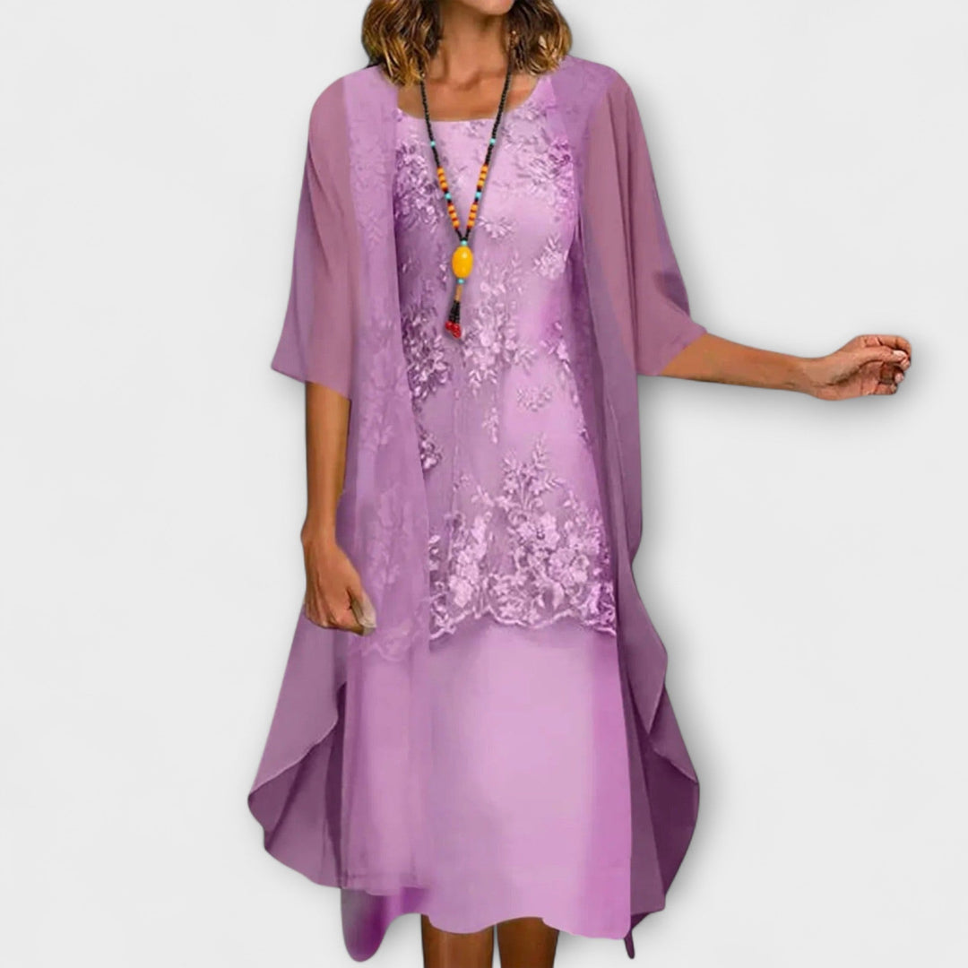 A woman wearing the Brenda floral embroidered dress with a V-neckline and softly flowing skirt.