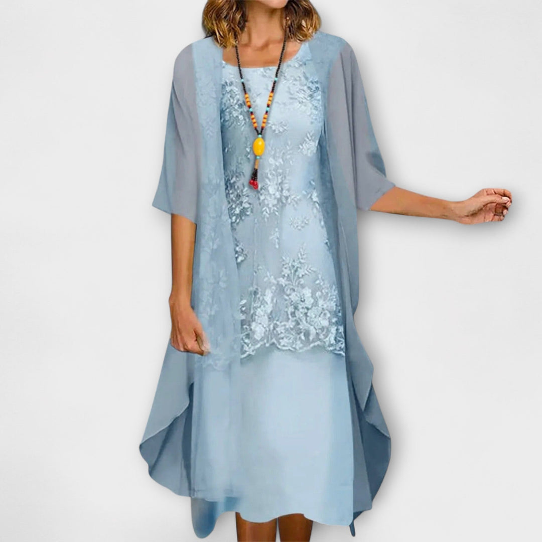 A woman wearing the Brenda floral embroidered dress with a V-neckline and softly flowing skirt.