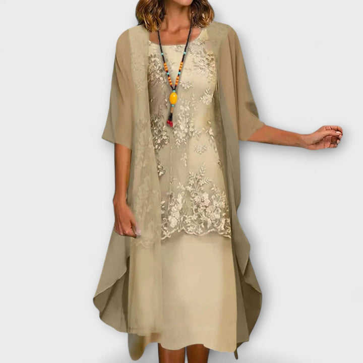 A woman wearing the Brenda floral embroidered dress with a V-neckline and softly flowing skirt.