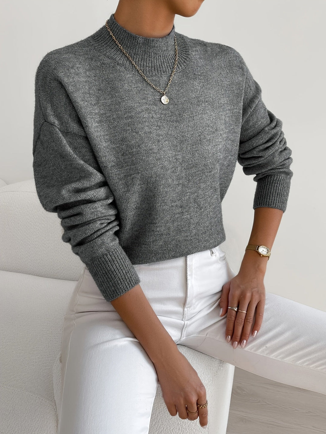 A woman wearing an elegant warm jumper with a modern stand collar, soft and refined.