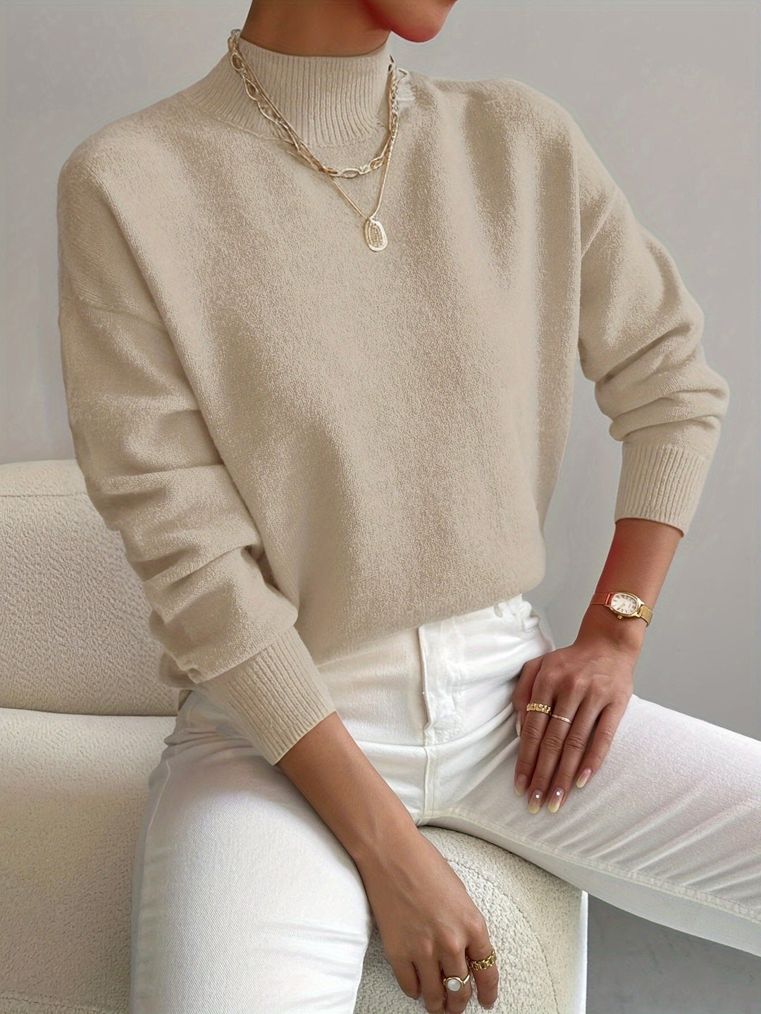 A woman wearing an elegant warm jumper with a modern stand collar, soft and refined.