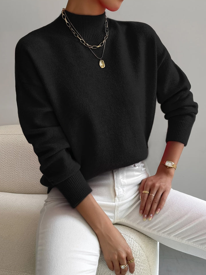 A woman wearing an elegant warm jumper with a modern stand collar, soft and refined.