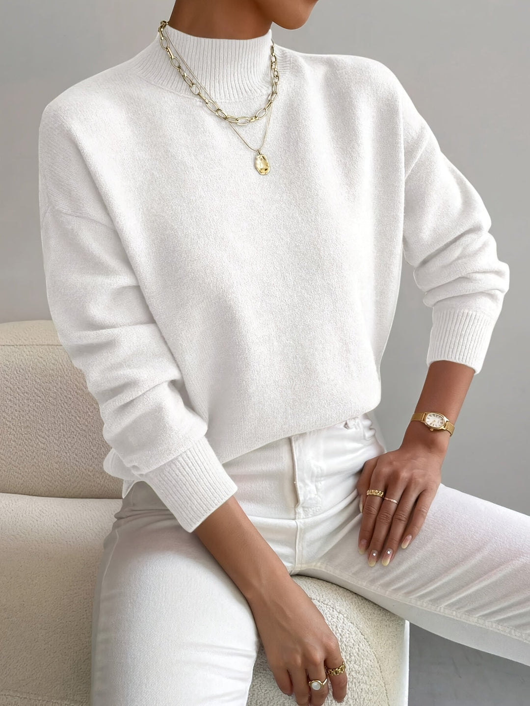 A woman wearing an elegant warm jumper with a modern stand collar, soft and refined.