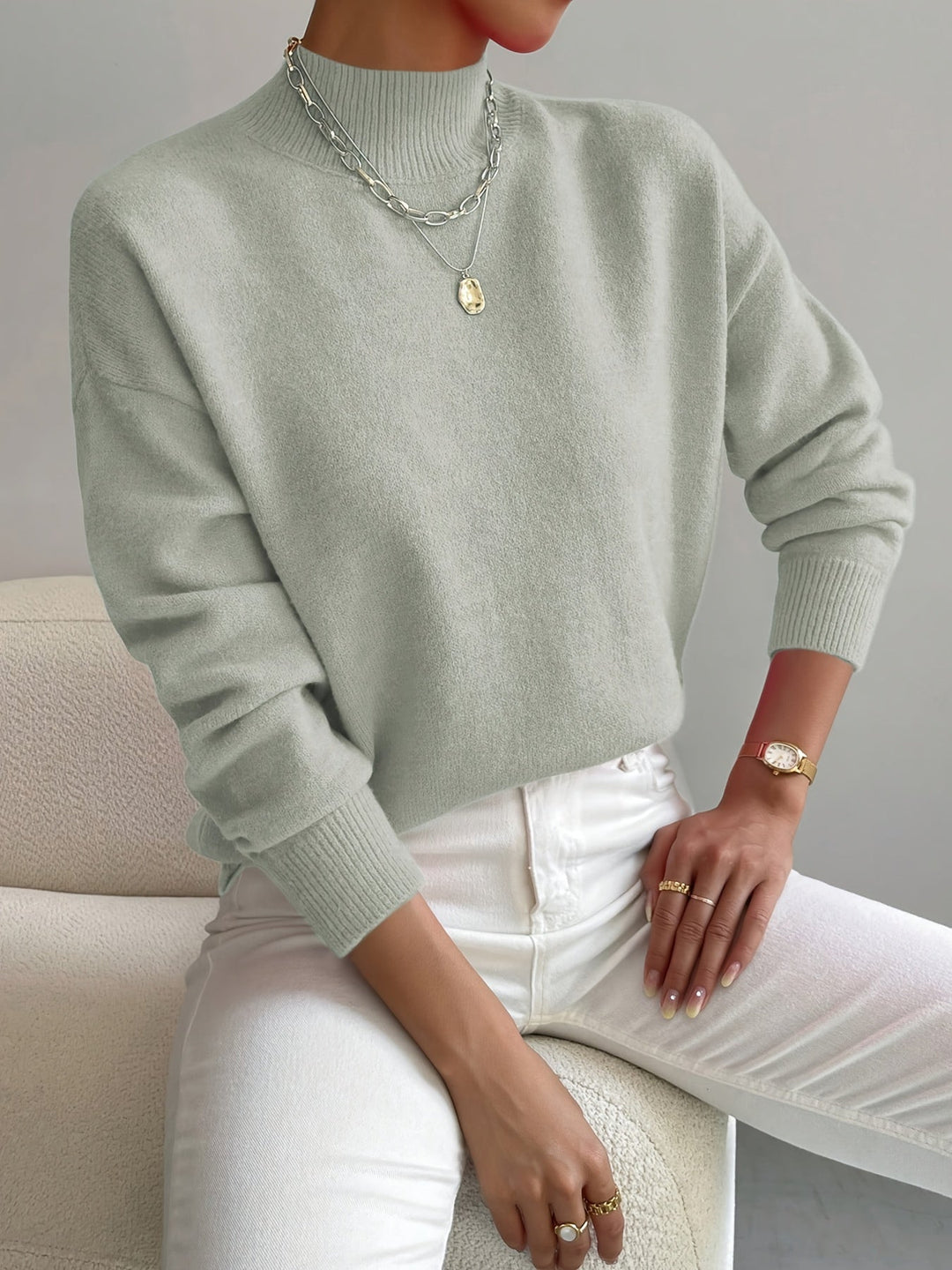 A woman wearing an elegant warm jumper with a modern stand collar, soft and refined.