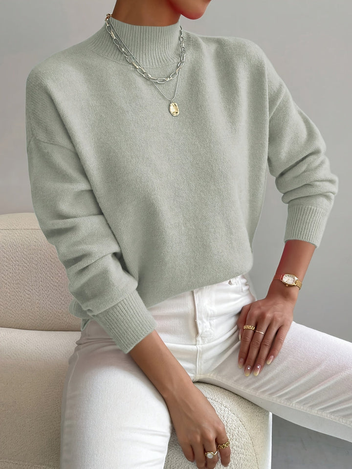 A woman wearing an elegant warm jumper with a modern stand collar, soft and refined.