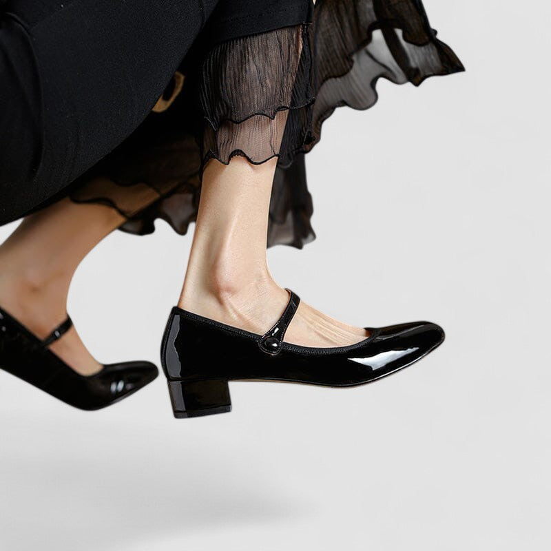 A woman wearing glossy black Mary Jane shoes with a low block heel, comfortable and steady during a day of errands.