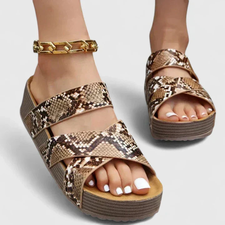 A woman strolling on a sunny street wearing beige woven comfort sandals with crossed straps.