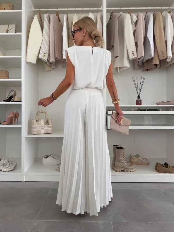 A woman wearing a structured sleeveless top with high-waisted pleated wide-leg trousers.
