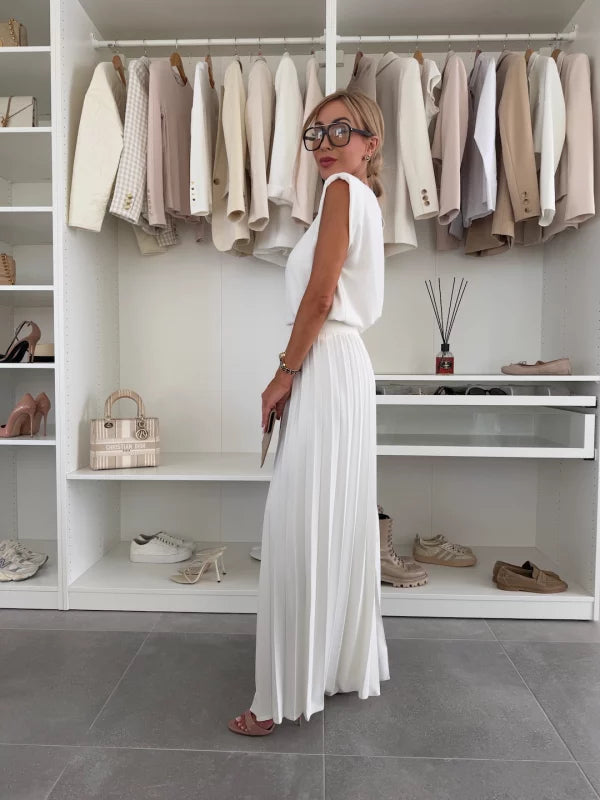 A woman wearing a structured sleeveless top with high-waisted pleated wide-leg trousers.