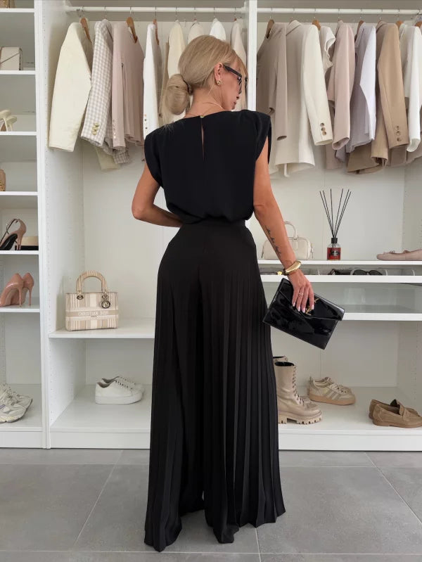 A woman wearing a structured sleeveless top with high-waisted pleated wide-leg trousers.
