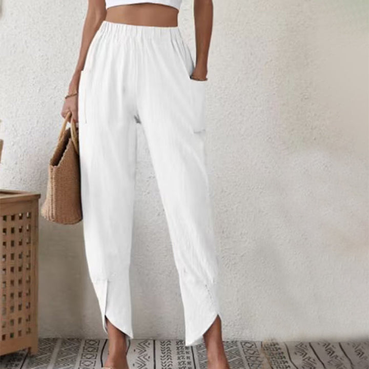 Woman wearing tapered trousers with a slit hem at the ankle, walking near the coast.