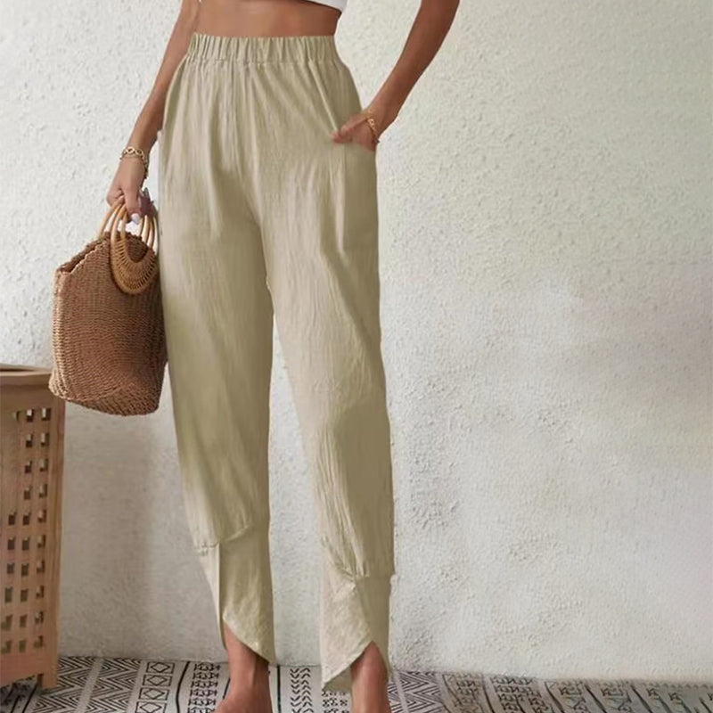 Woman wearing tapered trousers with a slit hem at the ankle, walking near the coast.