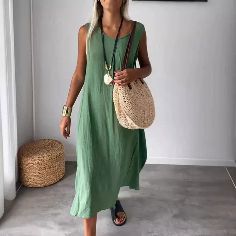 Woman wearing the Yvonne™ sleeveless flowing maxi dress with side pockets, relaxing outdoors on a warm day.