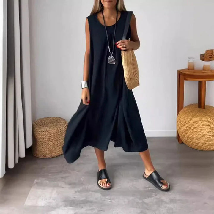 Woman wearing the Yvonne™ sleeveless flowing maxi dress with side pockets, relaxing outdoors on a warm day.