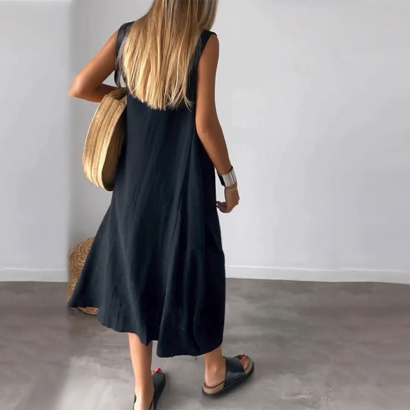 Woman wearing the Yvonne™ sleeveless flowing maxi dress with side pockets, relaxing outdoors on a warm day.