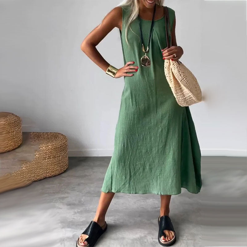 Woman wearing the Yvonne™ sleeveless flowing maxi dress with side pockets, relaxing outdoors on a warm day.