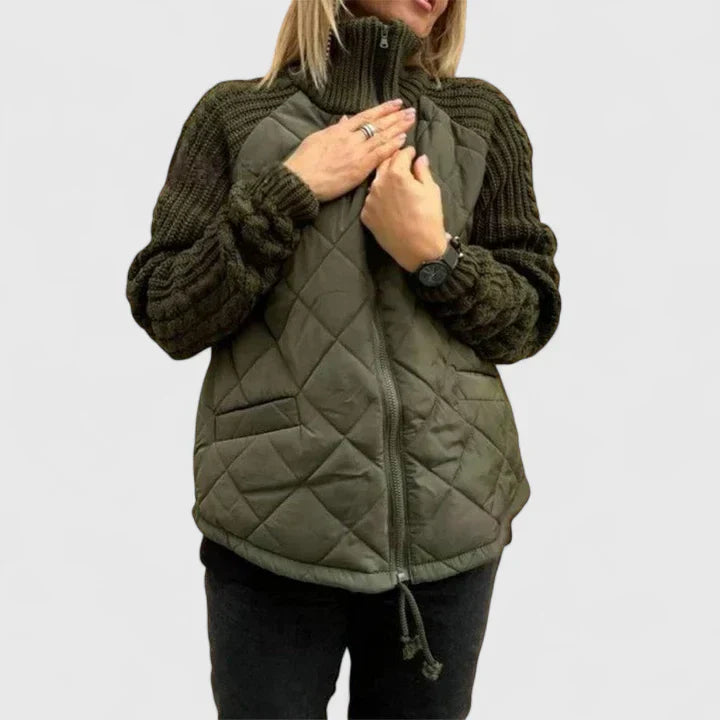 A woman wearing a patchwork hooded jacket with adjustable drawcords, hands in the pockets.