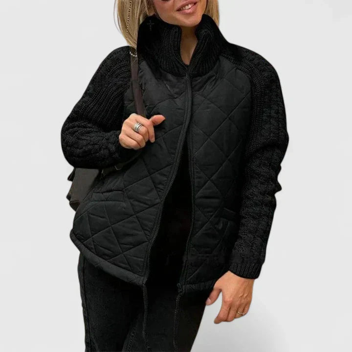 A woman wearing a patchwork hooded jacket with adjustable drawcords, hands in the pockets.