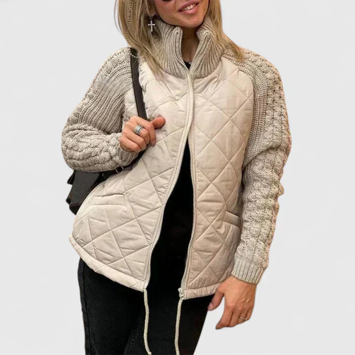 A woman wearing a patchwork hooded jacket with adjustable drawcords, hands in the pockets.