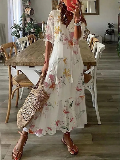 Woman wearing the Colette™ boho maxi dress with fringe details and a V-neckline, relaxed in a warm outdoor setting.