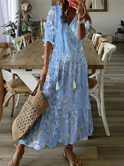 Woman wearing the Colette™ boho maxi dress with fringe details and a V-neckline, relaxed in a warm outdoor setting.