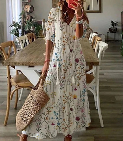 Woman wearing the Colette™ boho maxi dress with fringe details and a V-neckline, relaxed in a warm outdoor setting.
