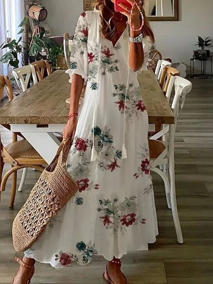 A woman wearing the Fiona boho midi dress with tassel ties at the neckline and a ruffled skirt.