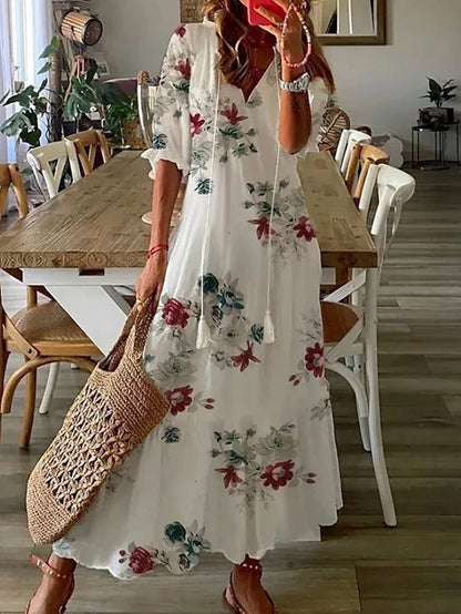 Woman wearing the Colette™ boho maxi dress with fringe details and a V-neckline, relaxed in a warm outdoor setting.