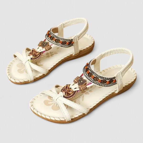 A woman walking comfortably outdoors in cushioned wide-fit orthopaedic sandals with a beaded T-strap and stretch slingback.