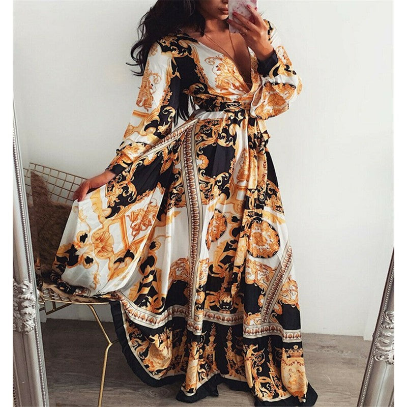 Woman at golden hour wearing the Tessa vintage print maxi dress with a waist belt and long statement sleeves.