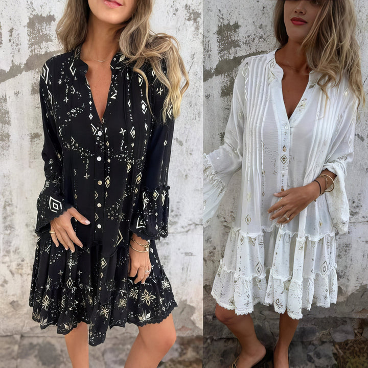 A woman wearing a black boho dress with a cream diamond-and-star print, flared sleeves and a tiered hem.