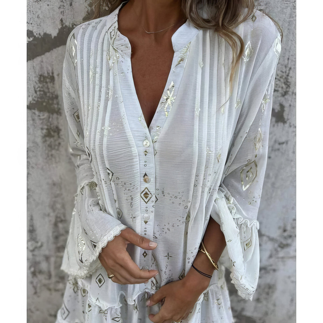 A woman wearing a black boho dress with a cream diamond-and-star print, flared sleeves and a tiered hem.