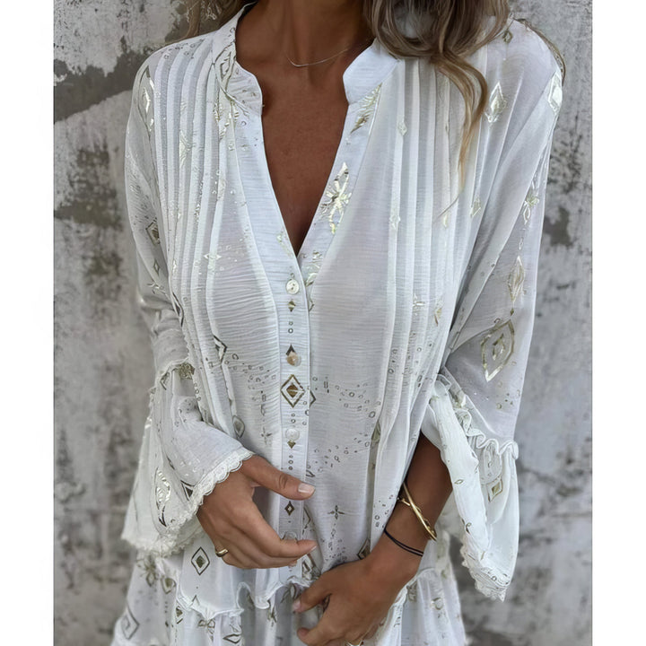 A woman wearing a black boho dress with a cream diamond-and-star print, flared sleeves and a tiered hem.