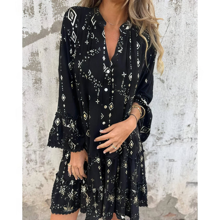 A woman wearing a black boho dress with a cream diamond-and-star print, flared sleeves and a tiered hem.