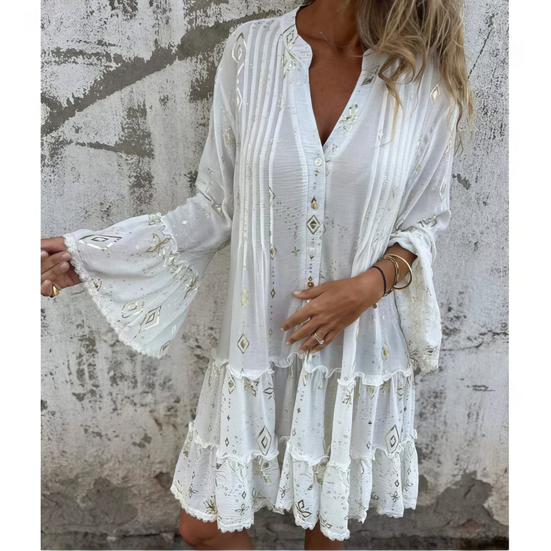 A woman wearing a black boho dress with a cream diamond-and-star print, flared sleeves and a tiered hem.