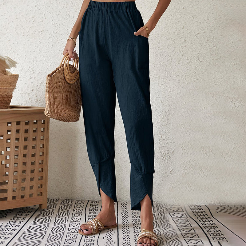 Woman wearing tapered trousers with a slit hem at the ankle, walking near the coast.