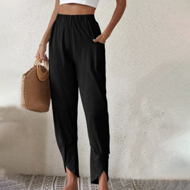 Woman wearing tapered trousers with a slit hem at the ankle, walking near the coast.