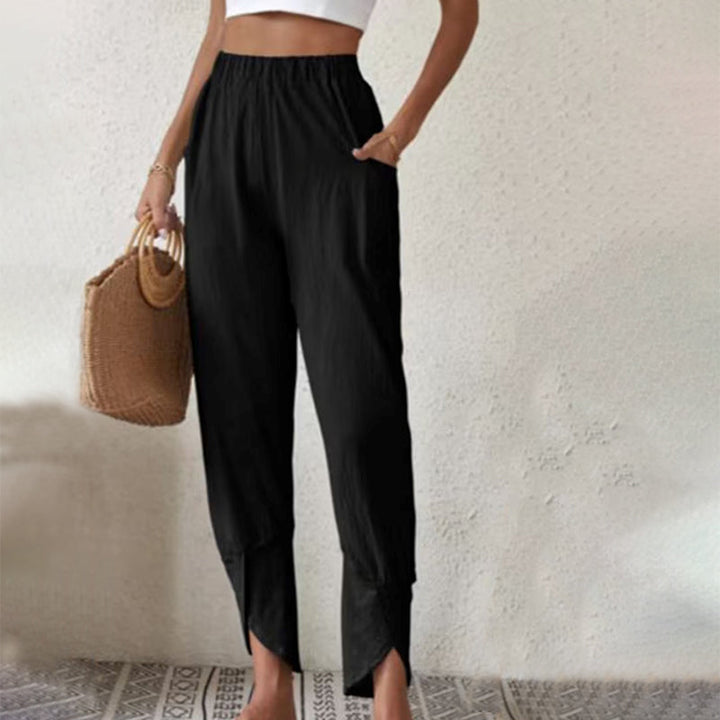 Woman wearing tapered trousers with a slit hem at the ankle, walking near the coast.